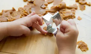 Dziecko używa metalowej foremki do ciastek, ćwicząc zagadki sensoryczne jak odgadywać przedmioty z zamkniętymi oczami.