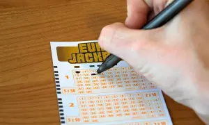 Ręka wypełnia kupon Eurojackpot. Syndykat w Eurojackpot, koszty podziału kuponu systemowego na 10 osób.