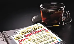 Zdrapka "Białe Złoto" z szansą na wygraną 200 000 zł leży obok kubka z herbatą.
