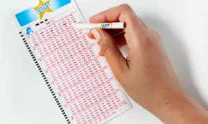 Dłoń z ołówkiem zaznacza liczby na kuponie Lotto. Zastanawiasz się, lotto ile jest do wygrania?