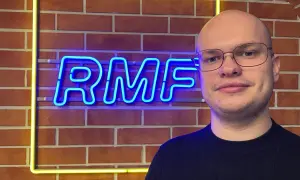 Mężczyzna w okularach stoi przed neonowym napisem RMF FM. Ile jest sejfów w RMF FM? Tego nie wiemy, ale na pewno jest tu dużo dobrej muzyki!