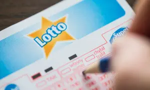 Ręka zaznacza liczby na kuponie Lotto. Planujesz grać w lotto w grupie? Dowiedz się, jak sporządzić umowę syndykatu.
