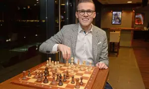 Mężczyzna w okularach gra w szachy, dowodząc, dlaczego gra w szachy i krzyżówki to najlepszy duet treningowy dla umysłu.