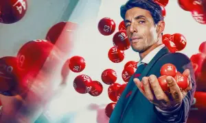 Mężczyzna w garniturze trzyma kulki lotto. Dowiedz się, jak legalnie grać w lotto w dużej grupie znajomych, tworząc syndykat loteryjny.