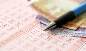 Długopis i banknoty na kuponie lotto. Dowiedz się, jak zorganizować loterię promocyjną w firmie zgodnie z prawem.