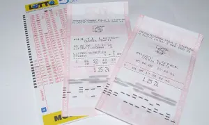 Kupony lotto, jeden z nich to duży lotek, leżą na stole.