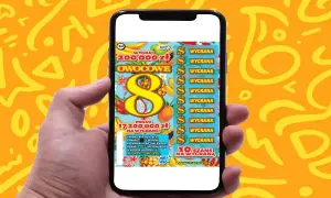 Ręka trzyma smartfon z grą "Owocowa eksplozja zdrapka". Na ekranie widać tropikalne owoce i symbol ósemki.