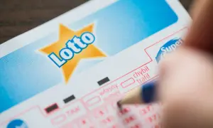 Kupon Lotto, ręka z ołówkiem. Dziedziczenie nagrody w loterii jak prawo traktuje kupony w spadku.