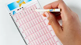 Ręka zaznacza liczby na kuponie Lotto. Aplikacja Lotto oferuje zniżki i promocje, pomagając łowić okazje.