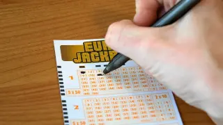 Ręka wypełnia kupon Eurojackpot. Syndykat w Eurojackpot, koszty podziału kuponu systemowego na 10 osób.