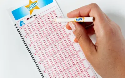 Ręka zaznacza liczby na kuponie Lotto. Aplikacja Lotto oferuje zniżki i promocje, pomagając łowić okazje.