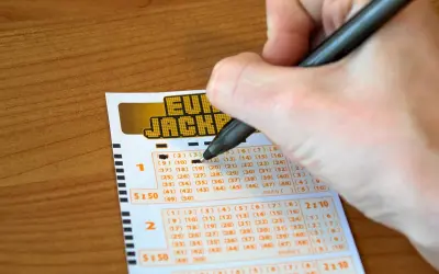 Ręka wypełnia kupon Eurojackpot. Syndykat w Eurojackpot, koszty podziału kuponu systemowego na 10 osób.