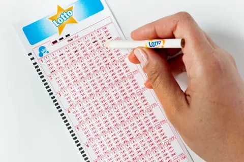 Ręka zaznacza liczby na kuponie Lotto. Aplikacja Lotto oferuje zniżki i promocje, pomagając łowić okazje.