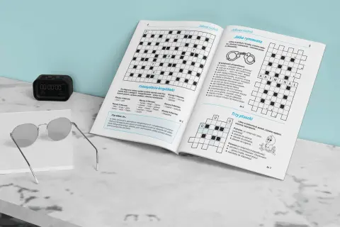 Jak rozwiązywać krzyżówki typu jolka krok po kroku? Na zdjęciu widzimy otwartą książkę z krzyżówkami, okulary i zegarek.