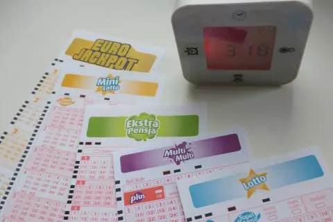Zegar pokazuje 3:18, a obok leżą kupony gier liczbowych: Eurojackpot, Mini Lotto, Ekstra Pensja, Multi Multi i Lotto. Sprawdź, do której godziny można wysłać lotto w kolekturze.