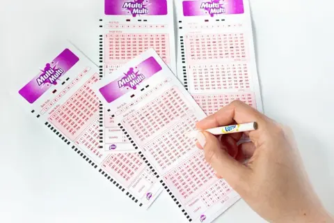 Ktoś zaznacza liczby na kuponach Multi Multi, zastanawiając się, czy warto dopłacać do stawki "plus".