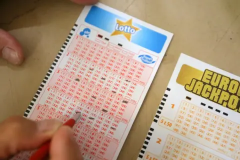 Ręka zaznacza liczby na kuponie Lotto. Dowiedz się, co zrobić po wygraniu szóstki w lotto krok po kroku.