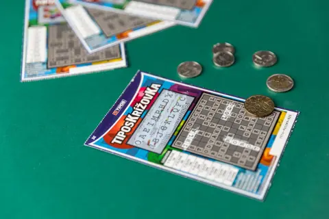 Zdrapek z krzyżówką i monetami na zielonym tle. Jak Totalizator Sportowy dba o bezpieczeństwo algorytmów drukowania zdrapek.