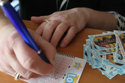 Ręka wypełnia kupon Lotto. Jak chronić swoją anonimowość po wygraniu milionów w krajowej loterii?