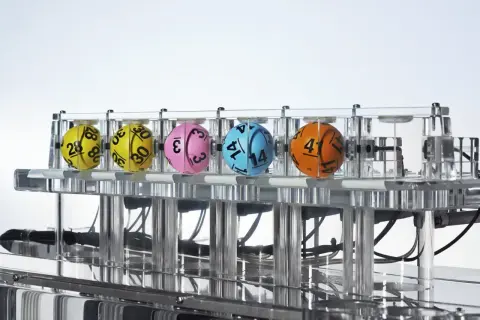 Kaskada Lotto: dlaczego zawsze losuje 12 liczb i jak sprawdzić wygraną? Kolorowe kule z numerami w maszynie losującej.