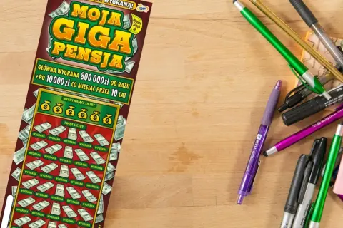 Zdrapka "Moja Giga Pensja" leży obok kolorowych długopisów. Czy uda się wygrać główną nagrodę?