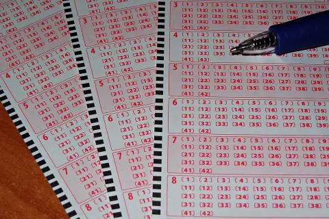 Zdrapki lotto z polami do zaznaczenia liczb i długopisem.
