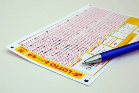 Kupon do gry Lotto z zaznaczonymi liczbami i długopisem. Zastanawiasz się, jak zablokować konto na stronie Lotto samowykluczenie na stałe?