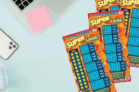 Trzy zdrapki "Super Linie" leżą obok telefonu i słuchawek. Szansa na wygraną 75 000 zł!