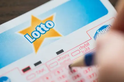 Kupon Lotto, ręka z ołówkiem. Dziedziczenie nagrody w loterii jak prawo traktuje kupony w spadku.
