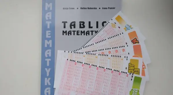 Matematyka w zdrapkach: jak obliczyć wartość oczekiwaną kuponu? Książka i kupony lotto na stole.