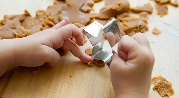 Dziecko używa metalowej foremki do ciastek, ćwicząc zagadki sensoryczne jak odgadywać przedmioty z zamkniętymi oczami.