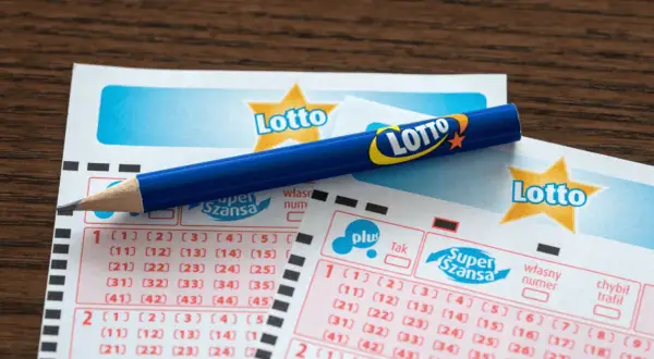 Uszkodzony kupon lotto z pralki. Czy da się odzyskać wygraną? Niebieski ołówek leży na kuponach.