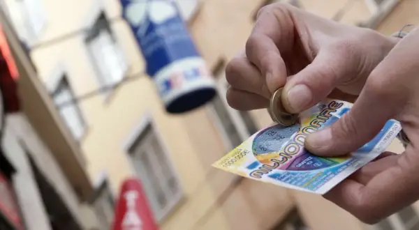 Ręka zdrapuje zdrapkę "Millionaire", krok po kroku po pieniądze. Czy to będzie wygrana pierwszego stopnia?