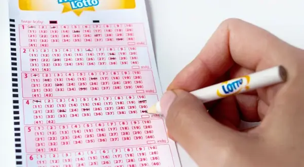 Dłoń z ołówkiem zaznacza liczby na kuponie Mini Lotto. Kto wie, ile za dwójkę w lotto plus?
