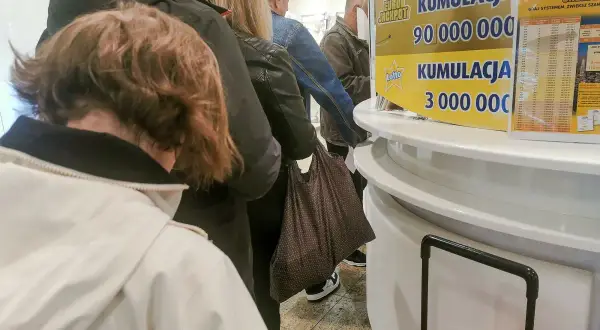Kolejka ludzi przed punktem Lotto. Czy kupowanie całej paczki zdrapek gwarantuje zwrot kosztów?