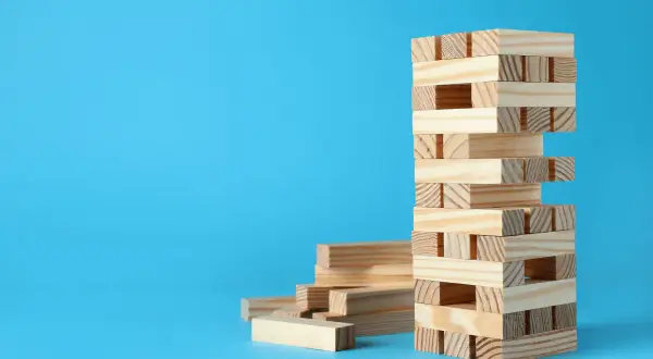 Wieża z klocków Jenga, obok stos luźnych elementów. Zagadki i prawa fizyki w grze, jak wygrywać w jengę bez przewracania.