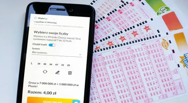 Smartfon z aplikacją do gry w lotto obok kuponów lotto.