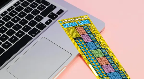 Zdrapka "Extra Linie" leży na laptopie. Czy uda się znaleźć wygrywające symbole i dodatkowe linie?