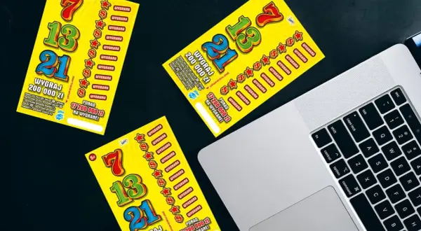 Żółte zdrapki Lotto leżą obok laptopa. Czy sprzedawca w kolekturze wie w której zdrapce jest wygrana?