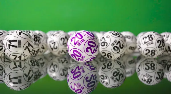 Kulki lotto na zielonym tle. Wygrana w lotto to szansa na bezpieczne inwestowanie pieniędzy i realizację marzeń.