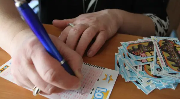 Ręka wypełnia kupon Lotto. Jak chronić swoją anonimowość po wygraniu milionów w krajowej loterii?