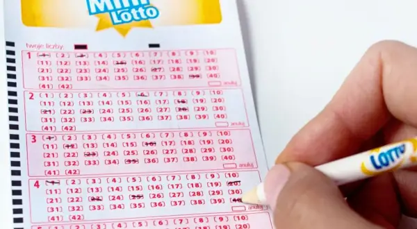 Ręka zaznacza liczby na kuponie Mini Lotto. To pokazuje, jak sprawdzana jest uczciwość bębna i certyfikaty maszyn losujących.