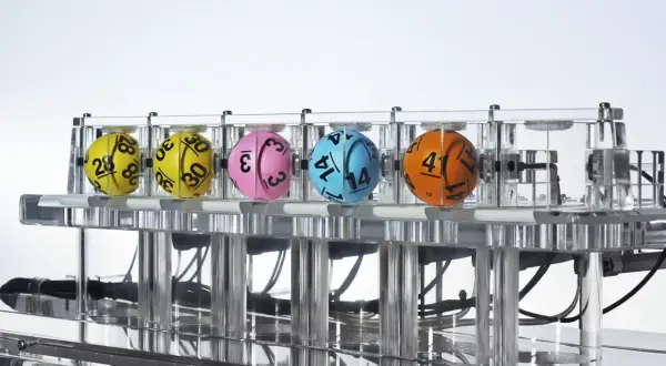 Kaskada Lotto: dlaczego zawsze losuje 12 liczb i jak sprawdzić wygraną? Kolorowe kule z numerami w maszynie losującej.