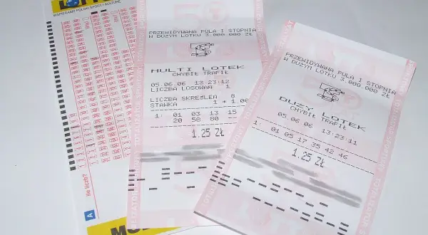 Kupony lotto, jeden z nich to duży lotek, leżą na stole.