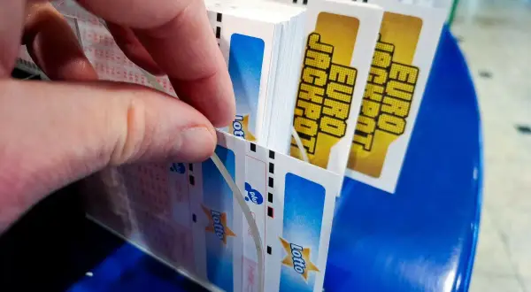 Dłoń wybiera kupony Lotto, marząc o multipasko wysokich wygranych.