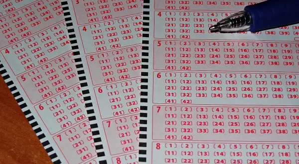 Zdrapki lotto z polami do zaznaczenia liczb i długopisem.