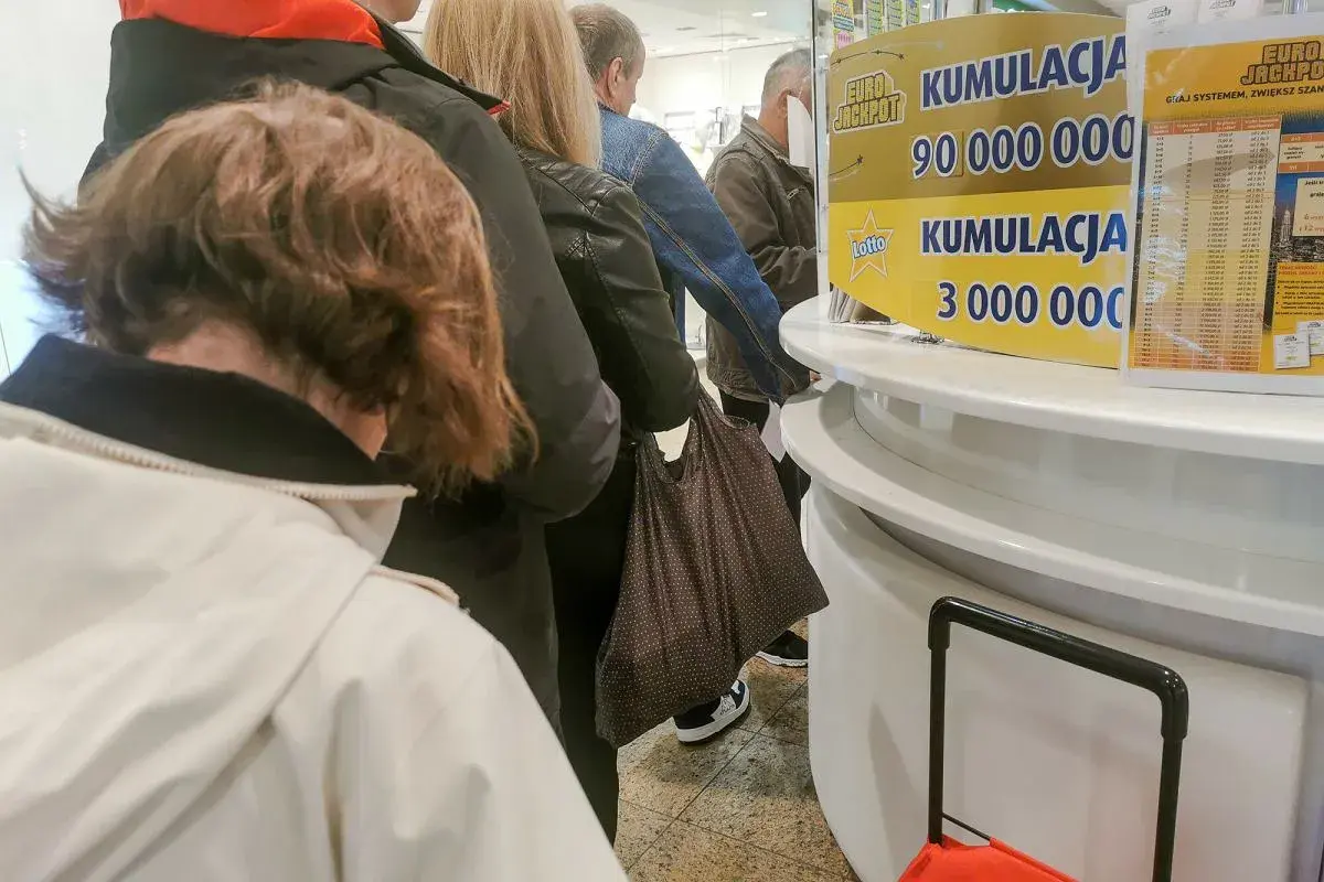 Kolejka ludzi przed punktem Lotto. Czy kupowanie całej paczki zdrapek gwarantuje zwrot kosztów?