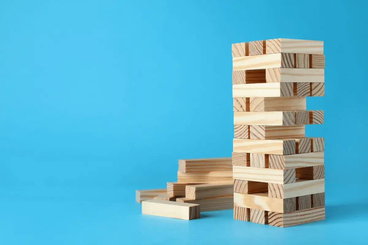 Wieża z klocków Jenga, obok stos luźnych elementów. Zagadki i prawa fizyki w grze, jak wygrywać w jengę bez przewracania.