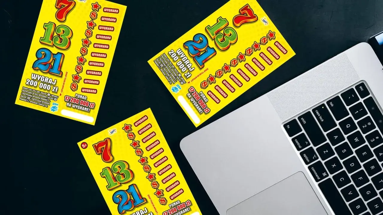 Żółte zdrapki Lotto leżą obok laptopa. Czy sprzedawca w kolekturze wie w której zdrapce jest wygrana?