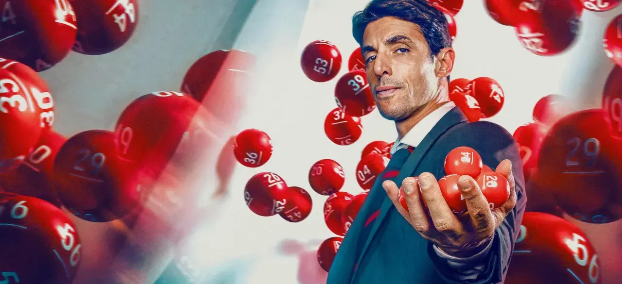 Mężczyzna w garniturze trzyma kulki lotto. Dowiedz się, jak legalnie grać w lotto w dużej grupie znajomych, tworząc syndykat loteryjny.